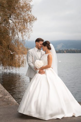 Braut und Bräutigam stehen vor einem See im Herbst