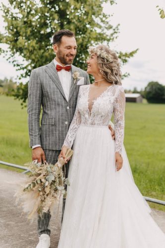 Braut und Bräutigam stehen zur Kamera Gewand und blicken sich an