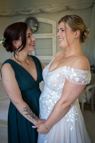Braut und Brautjungfer lächeln sich an