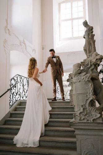 Braut nimmt Hand des Bräutigams auf der Treppe