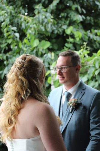 Braut steht mit dem rücken zur Kamera und schaut Bräutigam an