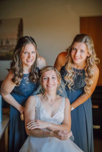 Braut und Brautjungfern tragen zartes Make Up und schauen in die Kamera