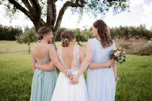 Braut und Brautjungfern stehen mit dem Rücken zur Kamera