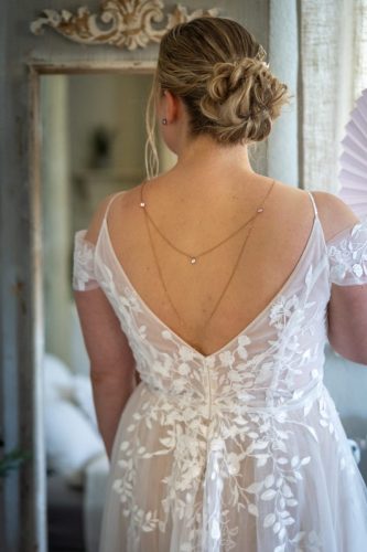 Braut steht mit dem Rücken zur Kamera und zeigt Ihre Hochsteckfrisur